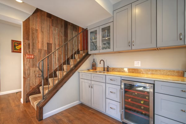 AFTER: Reclaimed barn wood wall paneling and a custom wrought iron handrail make a beautiful entrance to the lower level. A kitchenette with an underlit onyx countertop and wine cooler tailors the space for family and entertaining needs.